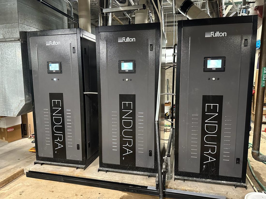 Three Fulton Endura condensing boilers installed side by side in a mechanical room